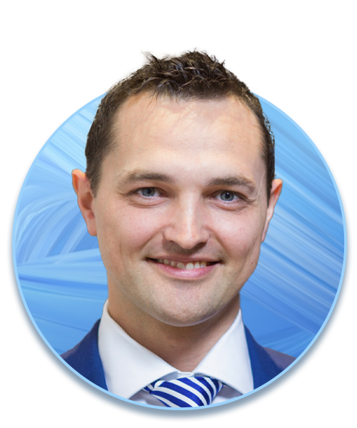 A man in a suit smiles, facing forward. He is framed within a circular blue background with abstract patterns, suggesting a professional or formal context.