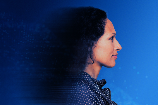 A woman with curly hair gazes to the side, displaying a thoughtful expression. The background is a gradient of blue with subtle abstract patterns, creating a futuristic atmosphere.