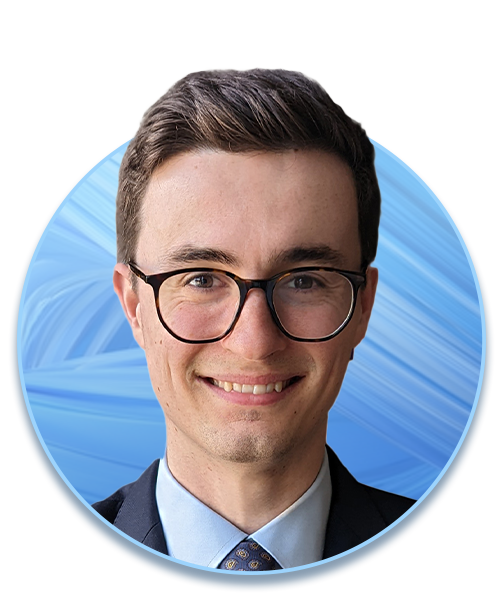 A young man with glasses smiles directly at the viewer. He is dressed in a dark suit and light blue shirt, set against a circular blue abstract background.